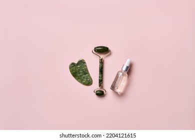 Cosmetic Beauty Product And Stone Massagers On Pink Background. Face Massage Skincare Concept