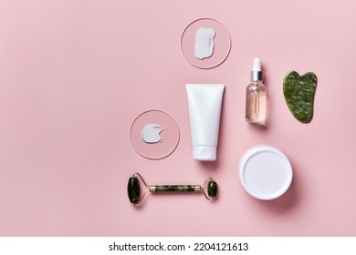 Cosmetic Beauty Products And Stone Massagers On Pink Background. Face Massage Skincare Concept