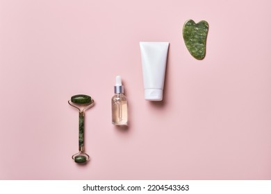 Cosmetic Beauty Products And Stone Massagers On Pink Background. Face Massage Skincare Concept