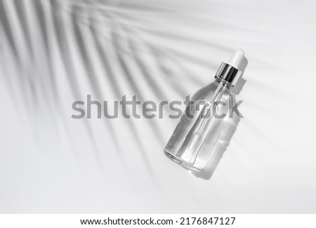 Cosmetic bottle with palm leaf shadow on white background. Blank label for branding mock-up.	