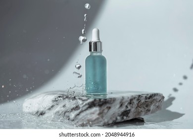 Cosmetic bottle with pipette standing on the stone. On white background with water drops.