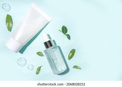 Cosmetic bottle with water drops, bubbles  and green leaves. Moisturizing, Facial Care, reparing and skincare product.  Top view flaylay copy space