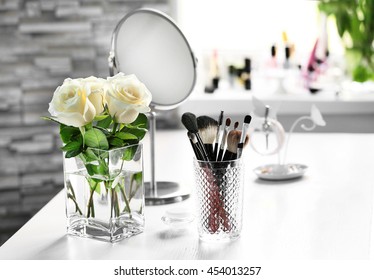 Cosmetic brushes with bouquet on light dressing table - Powered by Shutterstock
