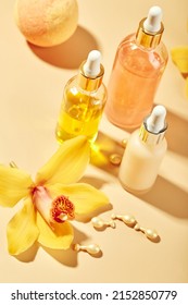 Cosmetic care products in glass bottles with orchid flowers - serums, cream, gel, oils. Concept for face and body care, spa, tropical relaxation. Cosmetics on colored background with hard shadows.