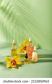 Cosmetic care products in glass bottles with orchid flowers - serums, cream, gel, oils. Concept for face and body care, spa, tropical relaxation. Cosmetics on colored background with hard shadows.