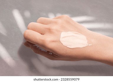 Cosmetic cc cream taster swatch smudge on woman hand on gray stone background