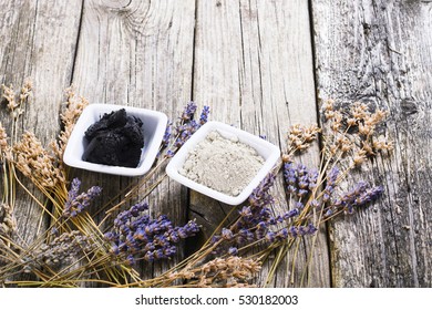 cosmetic clay powder and mud with dried lavender flowers on old weathered wooden table background