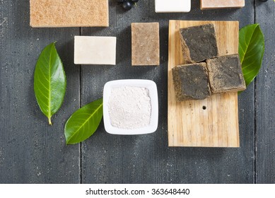 cosmetic clay, soaps, henna blocks, raw shea butter on black wood table - Shutterstock ID 363648440