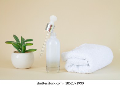 Cosmetic Clear Glass Open Serum Bottle Next To Plant And Towel