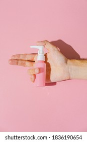 Cosmetic Cream For Face Blank Bottle In Hand. Bio Organic Product On Pink Background. Minimal Beauty And Spa Monochrome Gun Shoot Concept. 