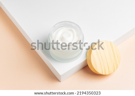 Cosmetic cream or moustirizer frosted glass open jar onwhite podium background. Open round glass jar with aesthetic swirls cream. Top view flatlay. Copy space