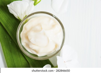 Cosmetic Cream With White Flowers On Bright Wooden Table