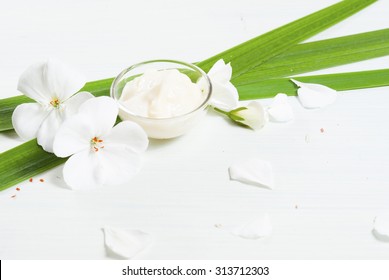 Cosmetic Cream With White Flowers On Bright Wooden Table