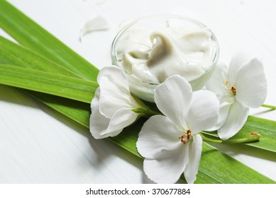 Cosmetic Cream With White Flowers On Bright Wooden Table