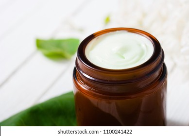 Cosmetic Creams And White Lilac Blossom On Bright Wooden Table Background