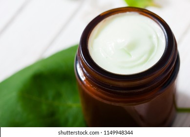 Cosmetic Creams And White Lilac Blossom On Bright Wooden Table Background