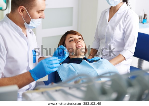 Cosmetic\
dentistry. Male doctor with his assistant inspecting woman patient\
teeth. Concept of medical staff and teamwork.\
