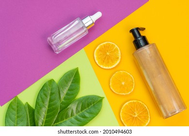 Cosmetic Flat Lay: Bronzer Body Glitter Cream, Face Serum And Natural Elements On A Combination Of Backgrounds Green, Purple And Yellow Colours