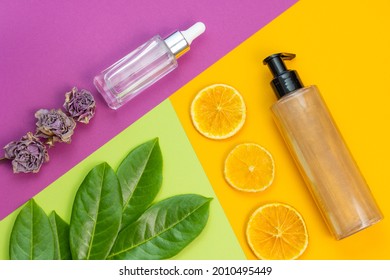 Cosmetic Flat Lay: Bronzer Body Glitter Cream, Face Serum And Natural Elements On A Combination Of Backgrounds Green, Purple And Yellow Colours