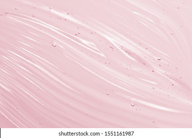 Cosmetic gel background. Face serum, clear beauty cream texture. Pink colored transparent skincare product close-up