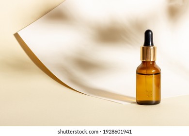 Cosmetic glass bottle with dropper with hard shadows. The concept of a beauty salon and natural cosmetics.