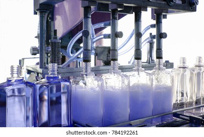 cosmetic industry, detail of filling glass bottle with blue eau de toilette