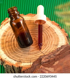 Cosmetic Ingredient Pycnogenol Or Pinus Pinaster In A Dark Bottle Stands On A Piece Of Pine Bark On A Green Background. Serum With Bark Extract For The Face. Skin Care. Concept Beauty Industry