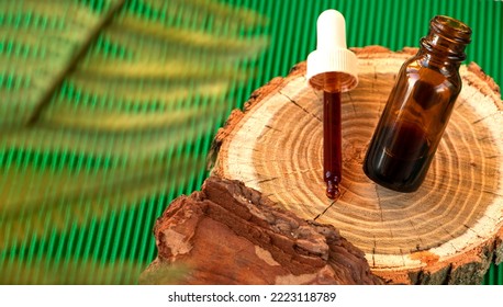 Cosmetic Ingredient Pycnogenol Or Pinus Pinaster In A Dark Bottle Stands On A Piece Of Pine Bark On A Green Background. Serum With Bark Extract For The Face. Skin Care. Concept Beauty Industry