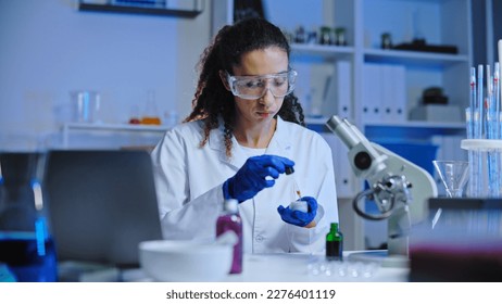 Cosmetic laboratory technician dripping plant serum in anti-aging cream, testing - Powered by Shutterstock