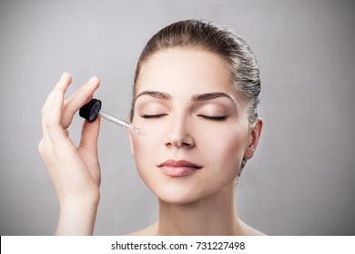 Cosmetic Oil Applying On Face Of Young Woman.