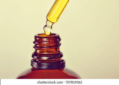 cosmetic oil. brown glass bottle and pipette with yellow oil on a light background. beige toning