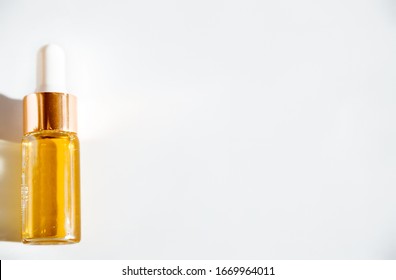 cosmetic oil in glass bottle with white pipette on white background with copy space