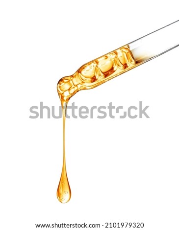 Cosmetic pipette with a yellow oily drop close up on white background 