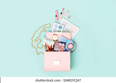 Cosmetic Products Flowing From Makeup Bag On Pastel Blue Background.  Flat Lay, Top View. Fashion Concept