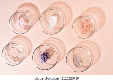 Cosmetic products, scrub, face serum and gel in many petri dishes on a pastel beige background. Cosmetics laboratory research concept