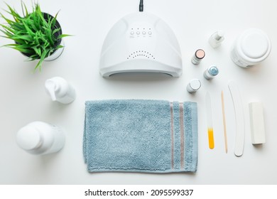 Cosmetic Products Set, Nail Hybrid Gels, UV Lamp, Green Leaves, Blue Towel On White Table. Spa, Manicure, Skin Care Concept. Flat Lay, Overhead View