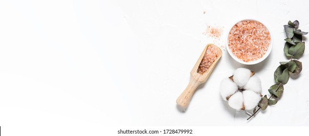 Cosmetic sea salt with eucalyptus twig and cotton flower on white background, long banner format, copy space for your design. Skin care concept.