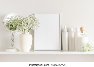 Cosmetic set on light dressing table.Beautiful flowers in a vase on a white wall background, mirror on a wooden shelf.