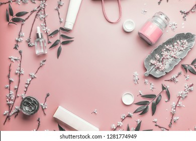 Kosmetisches und Hautpflegekonzept. Verschiedene Kosmetikprodukte auf pastellrosa Hintergrund mit Kirschblüte und Blättern, Draufsicht, Rahmen. Kopieren Sie Platz für Ihr Design. Beauty Blog-Layout. Flachlage
