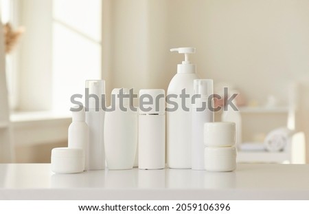Cosmetic skin care products of new female bodycare line for health, beauty and wellbeing. White mockup lotion bottles, cream jars and soap dispenser standing in row on table or shelf in beauty parlour