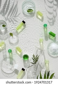 Cosmetic skincare background. Herbal medicine with green leaves. Natural sunlight, long shadows. Splashes of water, splashes. Chemical glassware, petri dishes, vials. Natural skincare background.