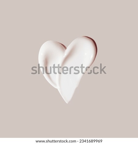 cosmetic smear of cream in the shape of heart on beige background 