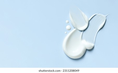 cosmetic smears of creamy texture on a blue background - Shutterstock ID 2311208049