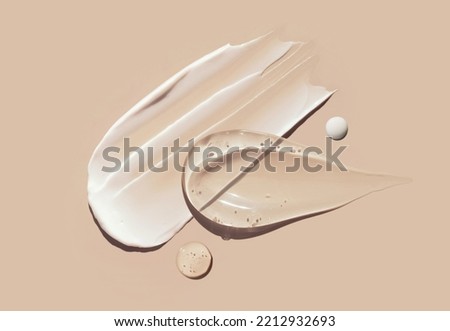 cosmetic smears of creamy texture on a pastel beige background