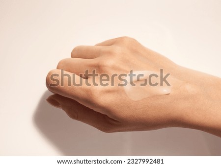 Cosmetic smudge texture on woman hand beige background