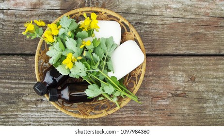 Cosmetic soap and tincture with celandine extract in a basket on a wooden background. - Shutterstock ID 1097984360