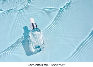 Kosmetische Spa-medizinische Hautpflege, Glas-Serumflasche mit Kollagen auf blauem Wasserhintergrund mit Wellen. Werbung für medizinisches Produkt zur Alterung, Feuchtigkeitsbefeuchtung und Reinigung.