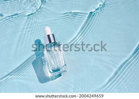 Cosmetic spa medical skincare, glass serum bottle with collagen on blue water background with waves. Advertising of medical product for anti-aging care, moisturizing and cleansing.