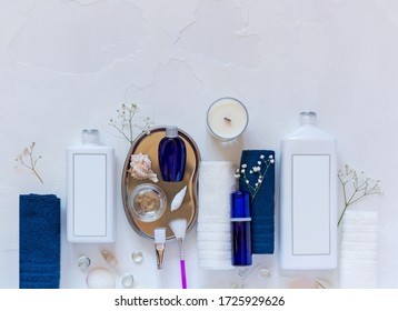 Cosmetic Spa mockup. Place your design. Blue and  white cosmetic bottles on folded towels with seashells, candles on a white background. Beauty salon, table with creams, soap, towels and candles