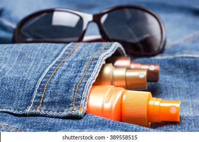 Cosmetic sunscreen products in jeans pocket on the background of sunglasses. Skin care cosmetics containing sun protection factor